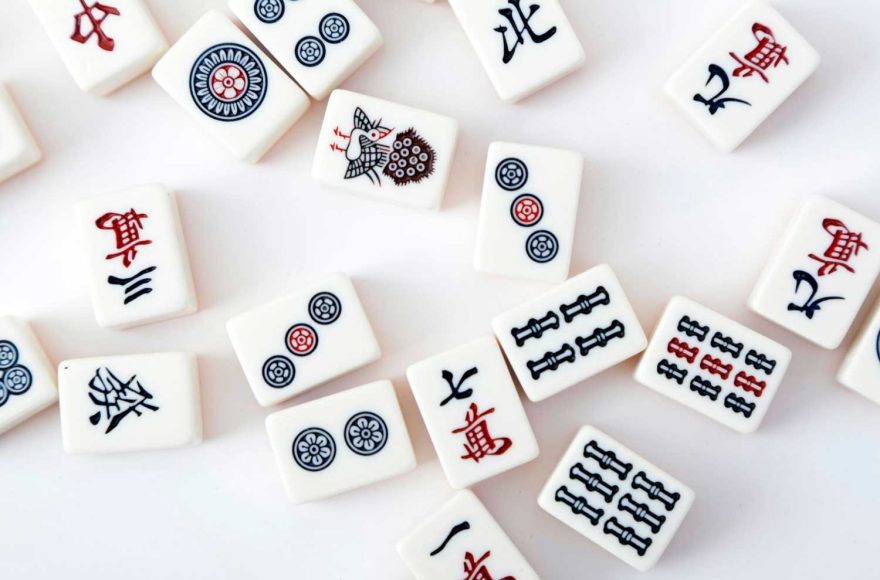Assorted mahjong tiles laid down in random order on a white table.